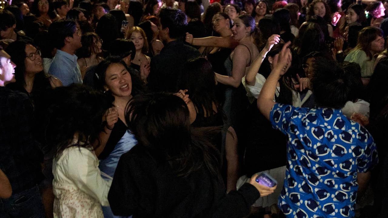 A large group of students dancing on a lawn after dark