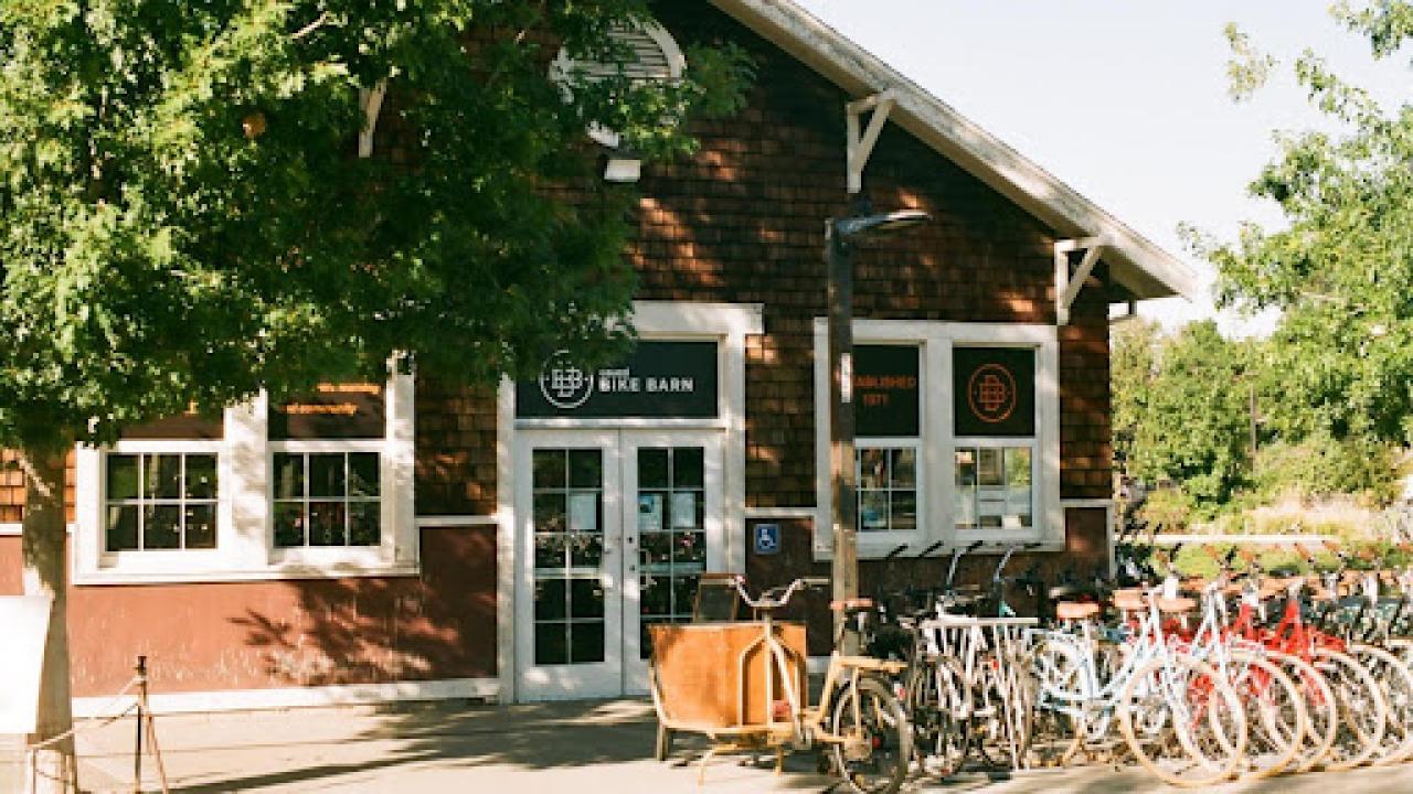 The Bike Barn entrance with a row of colorful bikes for sale in front of the shop.