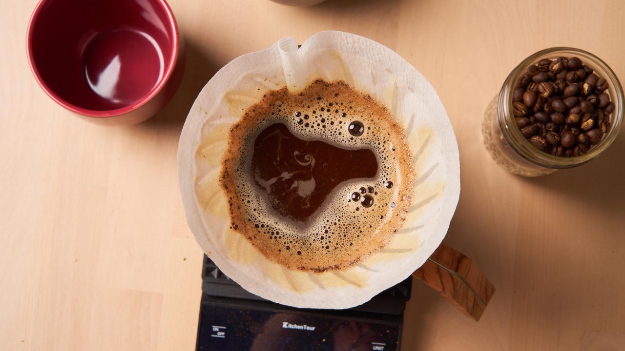 Image of a pour over coffee, a mug, and coffee beans.