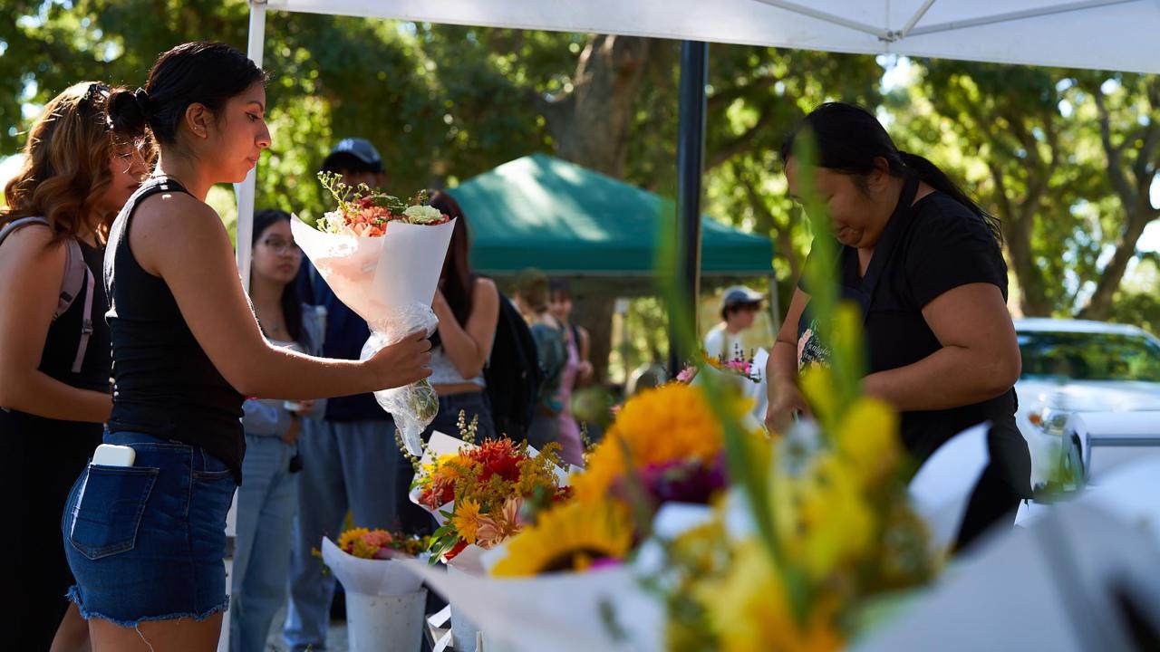 A woman grabbing flowers at the farmers market.