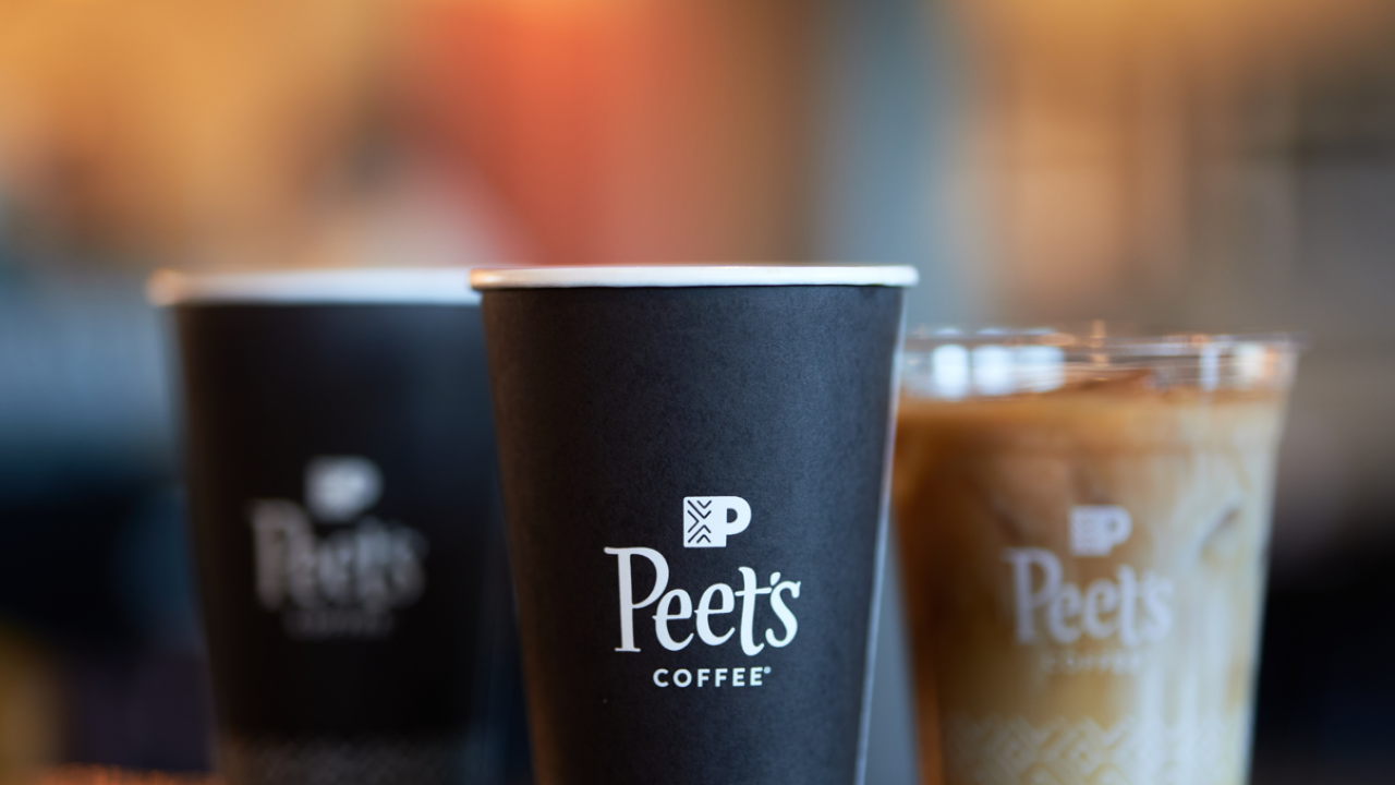 Two Peet's hot coffees and one ice coffee sitting on counter in front of softly blurred lights