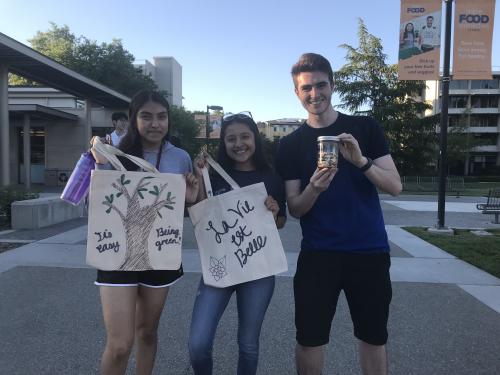 Three students holding tote bags