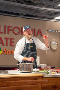 Chef Bob Walden cooking and holding up a tomato