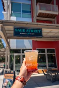 Someone holding up a Peet's iced drink in front of sage street market and cafe