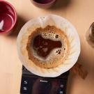 Image of a pour over coffee, a mug, and coffee beans.