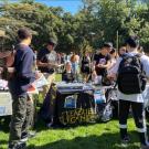 Students and club members learn about getting involved in on-campus registered organizations during the involvement fair on the quad. Students are sharing resources, club information, and sign-up links for recruitment. 